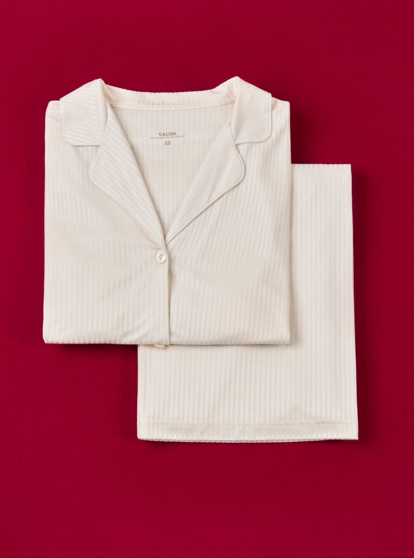 Classic pajamas in cream with a fine ribbed structure, stylishly presented against a festive background.