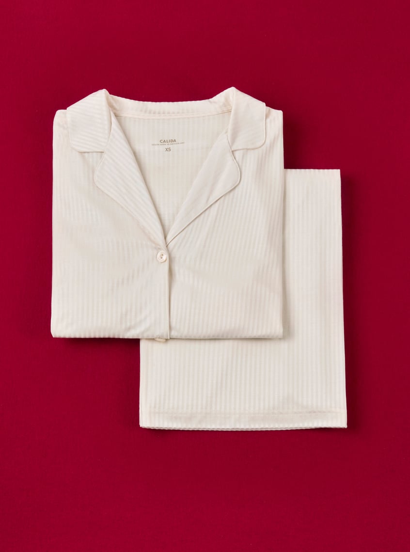 Classic pajamas in cream with a fine ribbed structure, stylishly presented against a festive background.