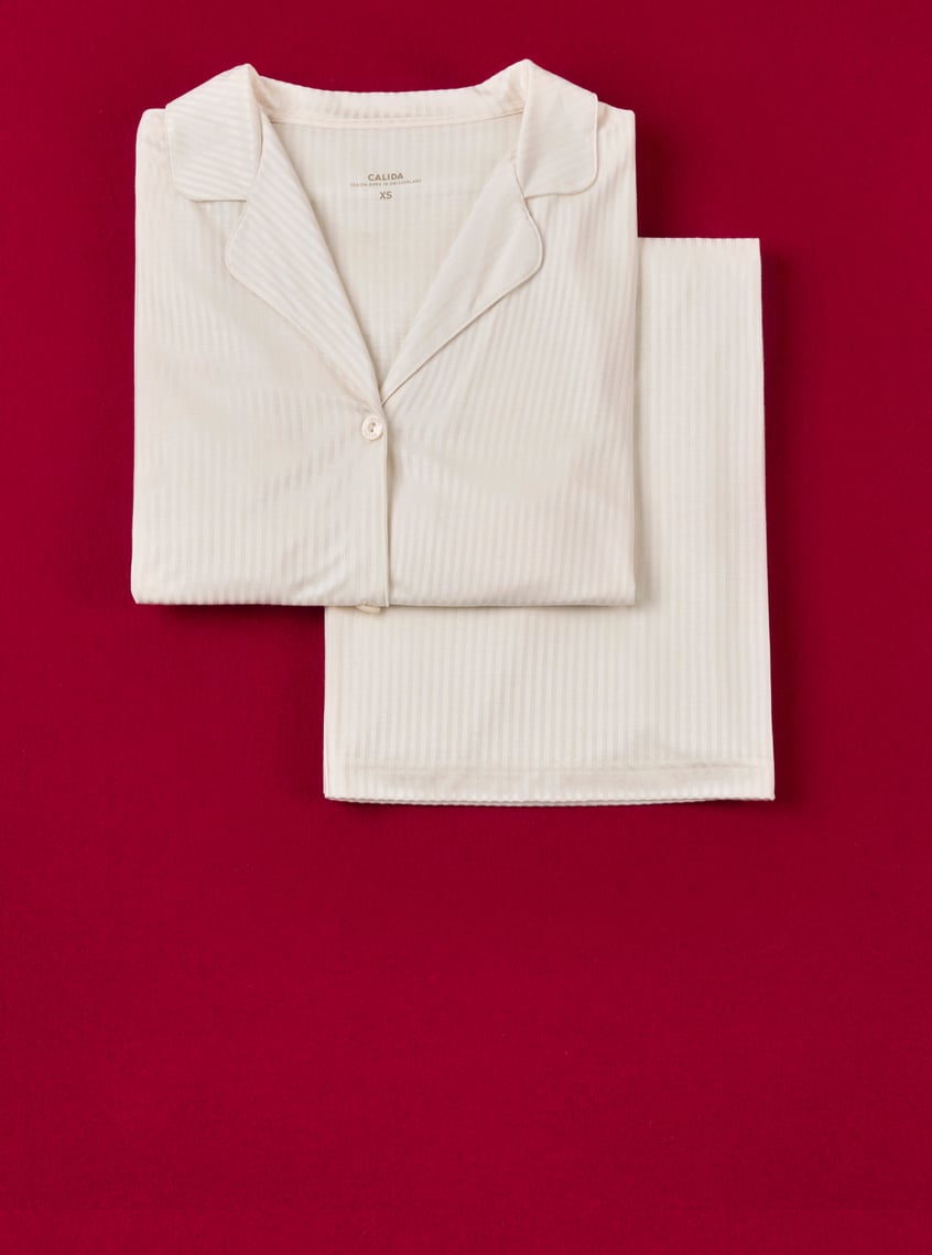 Classic pajamas in cream with a fine ribbed structure, stylishly presented against a festive background.