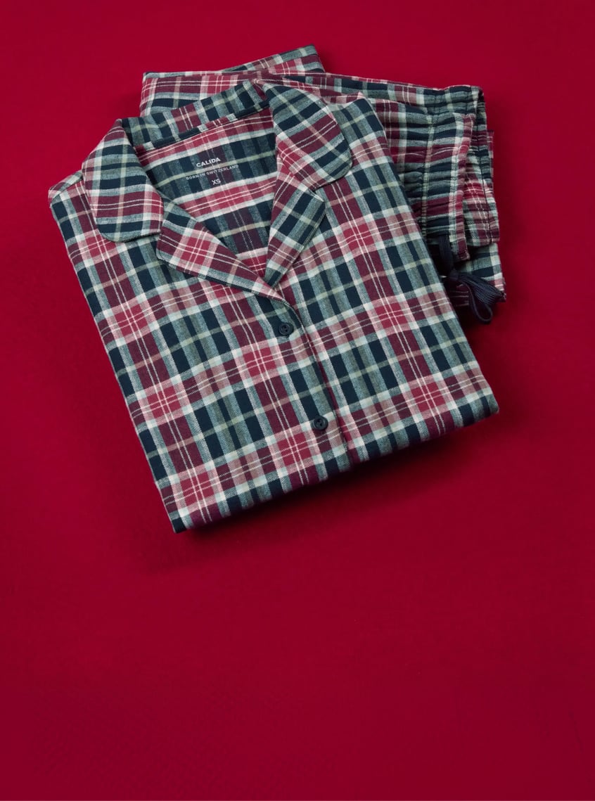 Classic pajamas with a checkered pattern in blue and burgundy tones, decoratively presented on a festive background.