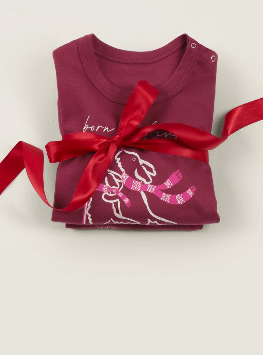 Children's sleepwear with a winter dog motif, festively arranged with a red gift ribbon.