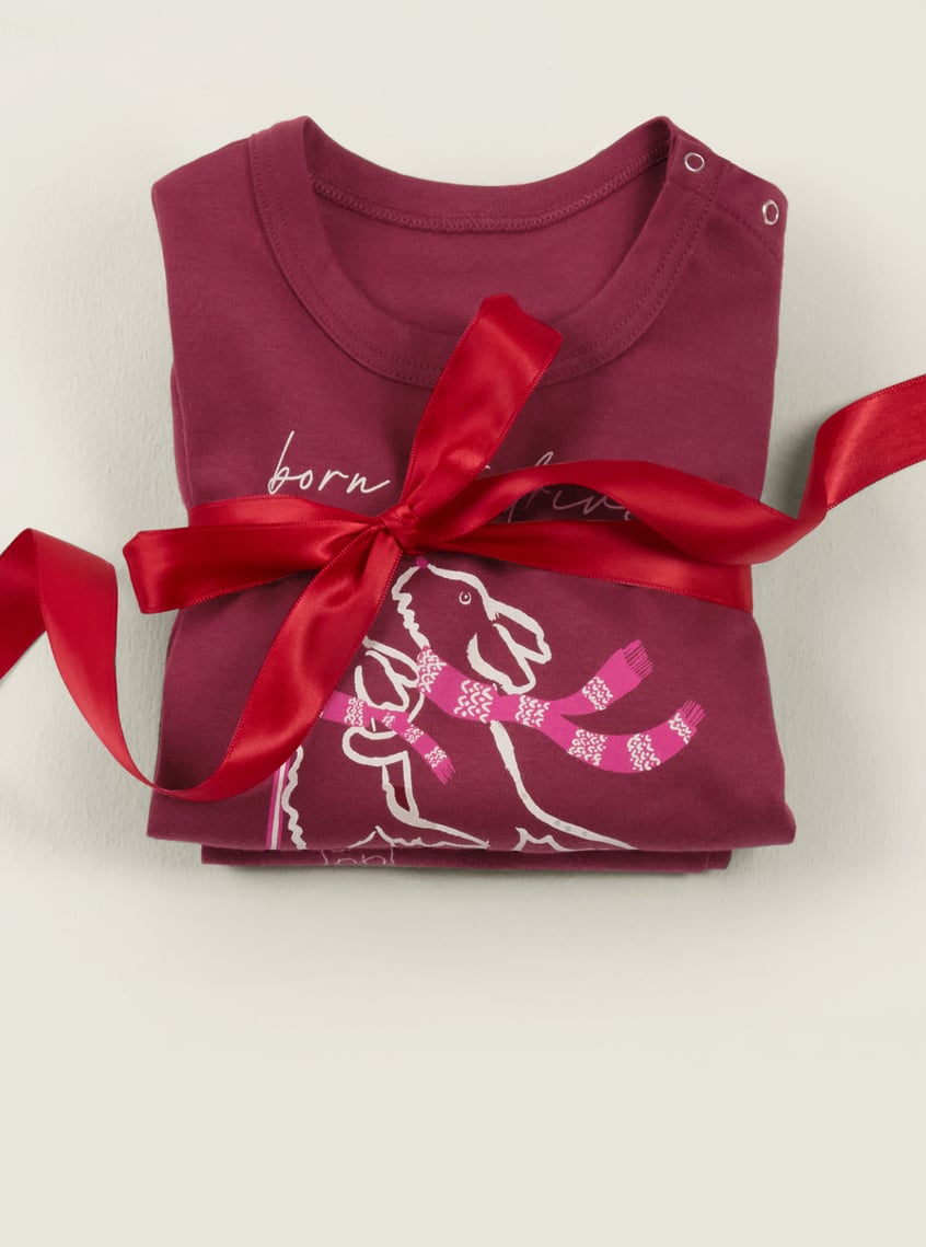 Children's sleepwear with a winter dog motif, festively arranged with a red gift ribbon.