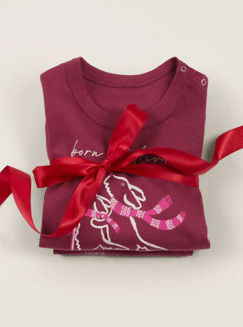 Children's sleepwear with a winter dog motif, festively arranged with a red gift ribbon.