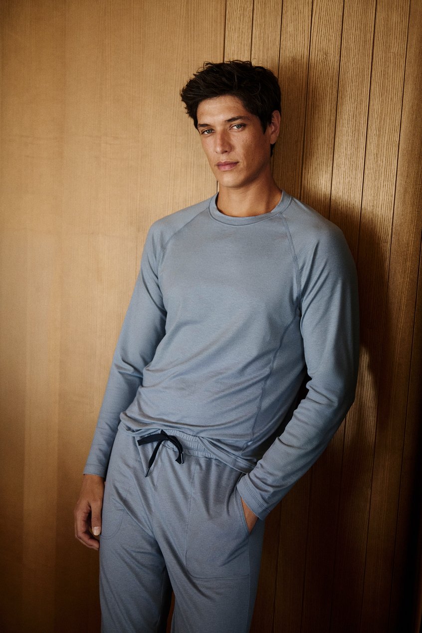 Männliches Model trägt einen blauen langen Pyjama der DEEPSLEEPWEAR Warming Kollektion im Homewear-Look.