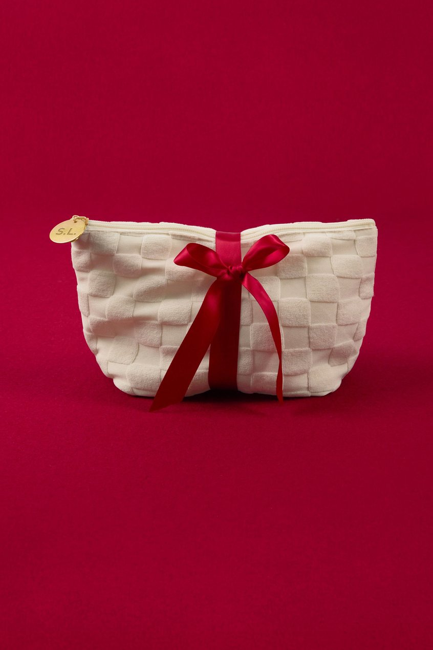 Cosmetic bag festively wrapped in front of a red background.