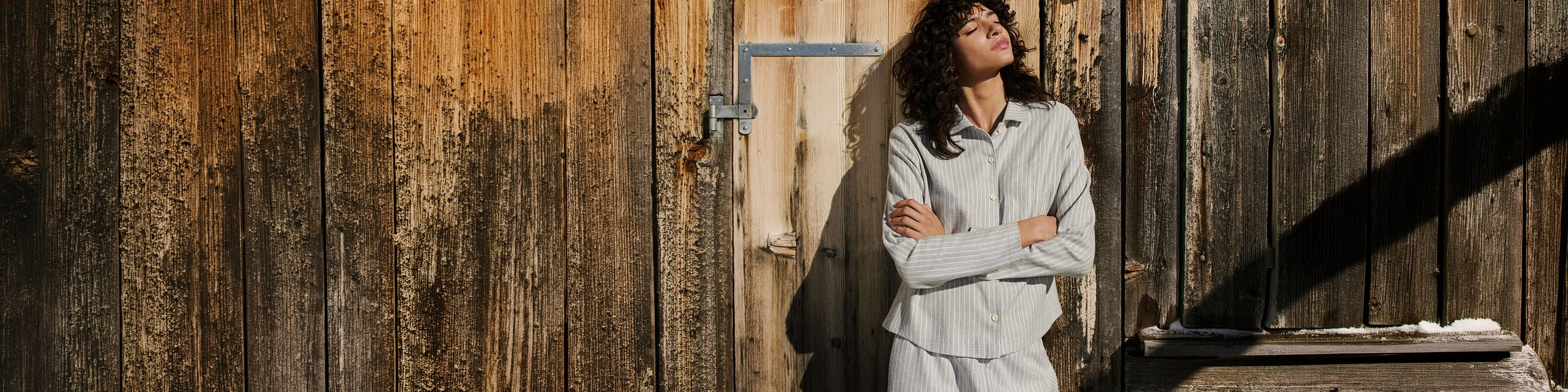 The model is standing relaxed, enjoying the sunshine while wearing a button-front flannel pyjama from the Flannel Dreams series.