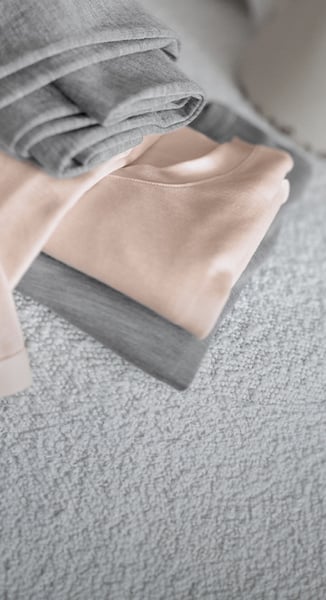 Es sind zwei Oberteile und zwei Leggings aus der Serie True Confidence in den Farben Rosa und Grau zu sehen.