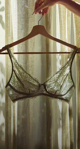 Zwei weibliche Models liegen in einem Bett und tragen florale Pyjamas der Marke Calida in Pastelltönen.