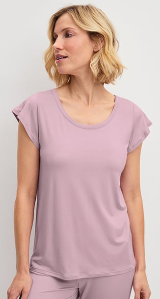 Die Dame trägt ein rosa Nachtwäsche-Set aus der Serie DSW Balancing und hält ein Kissen in der Hand.