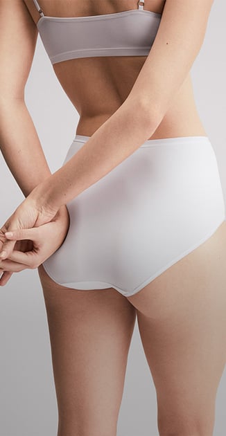 La donna è in posa con disinvoltura e indossa un bustier abbinato alle mutandine della linea Sleek Skin.
