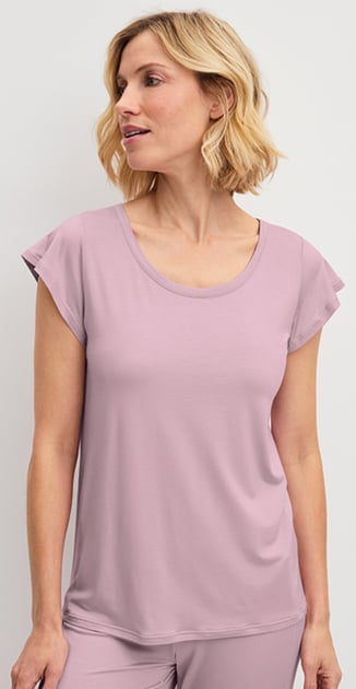 Die Dame trägt ein rosa Nachtwäsche-Set aus der Serie DSW Balancing und hält ein Kissen in der Hand.