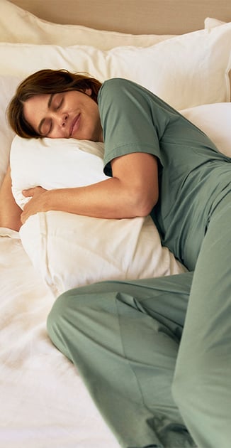 The lady is wearing a breathable pajama from the Deepsleepwear Balancing collection in green.
