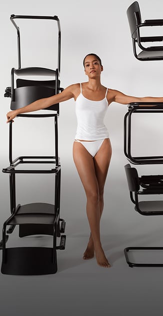 La dame porte un haut à bretelles fines avec la culotte tanga assortie de la série Sleek Skin en blanc.