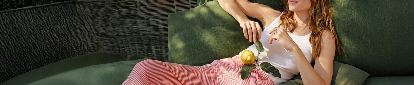  The image shows a model on an outdoor lounger wearing a white top and pink and white striped pyjama bottoms.