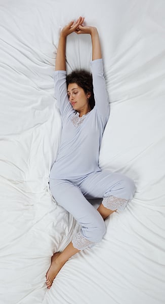 Das Model trägt wärmeregulierende Nachtwäsche der Serie Elegant Dreams in Hellblau mit Spitze