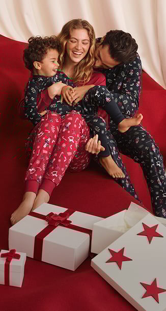 Das Bild zeigt eine Familie, die Pyjamas mit demselben Muster im Partnerlook trägt.