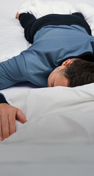 Zeigt ein männliches Model in einem Pyjama der Serie Relax Essentials