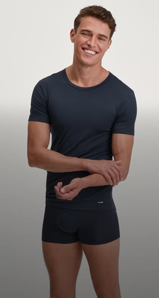 The man is wearing a short-sleeved, round-neck shirt from the Balanced Day range and matching boxer briefs in dark blue.