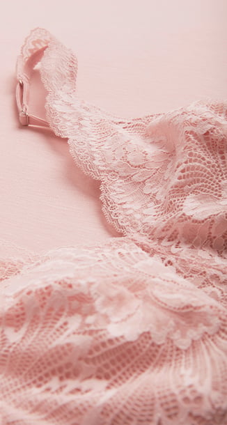 Zu sehen ist ein feminines Spitzennachthemd in sanftem Rosé.