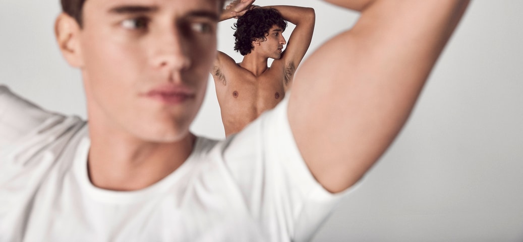Two people with raised arms against a bright background; focus on the underarm area as a symbolic image for removing sweat stains