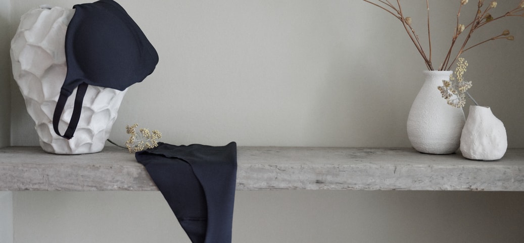 Lingerie bleu foncé CALIDA de la série Natural Skin, mise en scène sur une étagère minimaliste