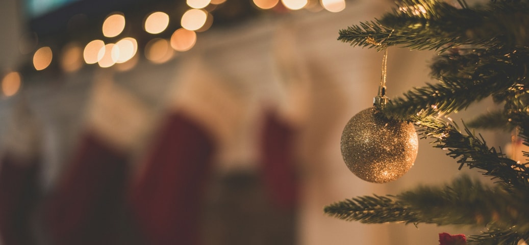 Primo piano di un albero di Natale decorato con sfera dorata, calze e luci sullo sfondo – focus: Natale rilassato