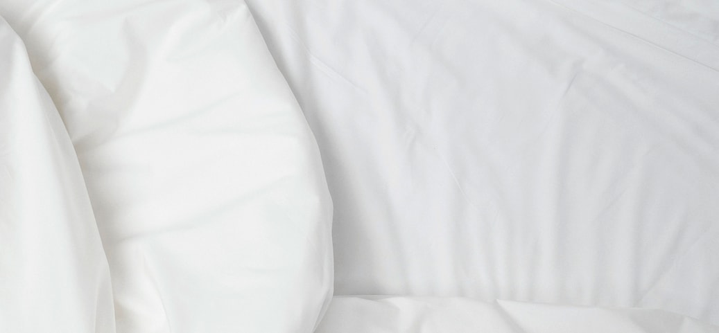 Close‑up of white, slightly wrinkled bed sheets
