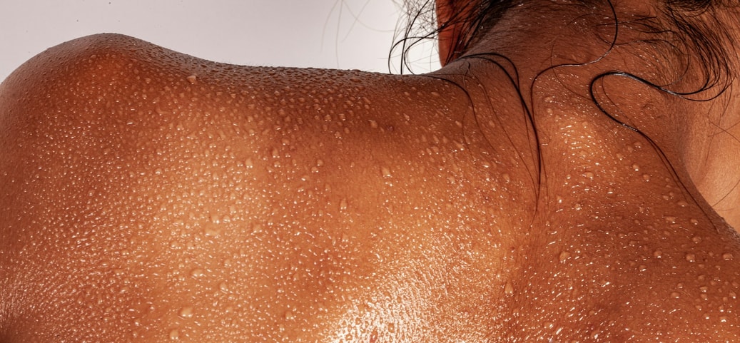 Close‑up of a sweaty back with visible moisture droplets symbolising heavy sweating