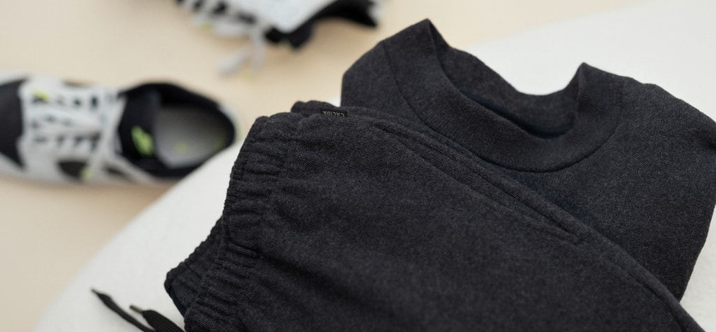CALIDA RMX LOUNGE TIME OFF Sweatshirt liegt auf einer weissen Couch. Im Hintergrund sieht man weisse Sneaker.