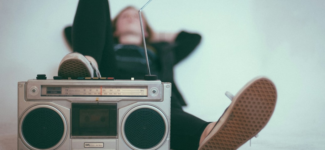 Person relaxes with a retro radio recorder and legs stretched out.