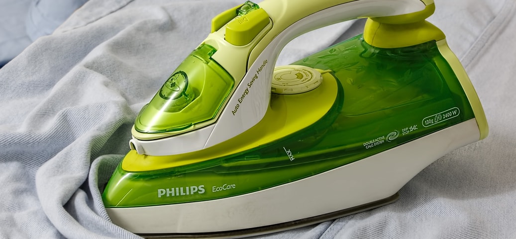 Ein grünes Philips-Bügeleisen auf einem Kleidungsstück – Tipps und Techniken für richtiges Bügeln leicht gemacht.
