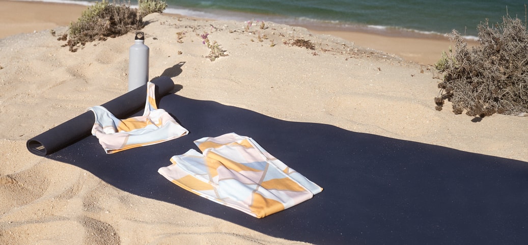 Yoga mat with yoga clothing from CALIDA on the beach