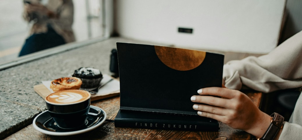 Digital detox in a café - a person with a book and coffee, without digital distractions.