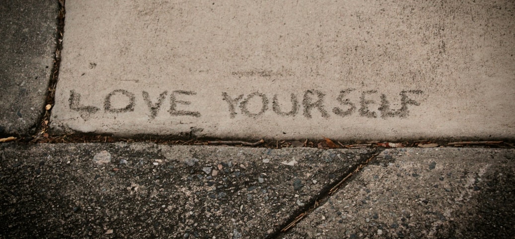 The words ‘LOVE YOURSELF’ engraved in the concrete - learn to love yourself and value yourself.
