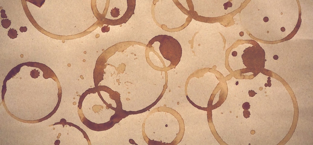 Mehrere braune Kaffeeflecken auf Papier, die den typischen Kaffeeflecken auf Kleidung ähneln.