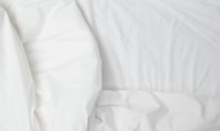 Close‑up of white, slightly wrinkled bed sheets