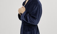 Personne portant un peignoir CALIDA bleu foncé de la collection After Shower, se tenant de côté contre un fond clair.