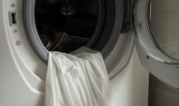 Machine à laver ouverte. Dans le tambour se trouve un haut blanc.