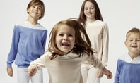 Four children in age-appropriate pyjamas looking happily into the camera symbolise children's need for sleep and the importance of comfortable nightwear for restful sleep