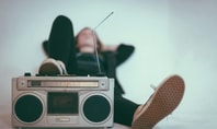 Person relaxes with a retro radio recorder and legs stretched out.