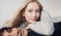 A relaxed couple in CALIDA clothing presenting the onion look. The woman is wearing a grey jumper, the man a dark top, both looking relaxed and stylish.