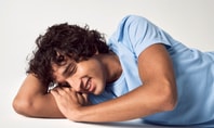 Man lies on his arm with his eyes closed. He is wearing a light blue sleep shirt from CALIDA.