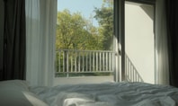 Geöffnetes Fenster mit Blick ins Grüne – Symbol für Lüften vor dem Schlafen für ein besseres Raumklima.