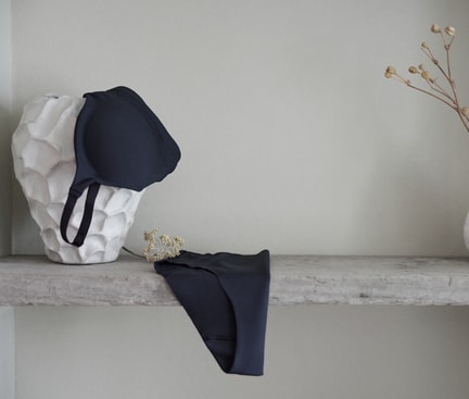 Lingerie bleu foncé CALIDA de la série Natural Skin, mise en scène sur une étagère minimaliste