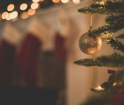 Close-up of a festively decorated Christmas tree with golden bauble, stockings and lights in background – focus: relaxed Christmas time