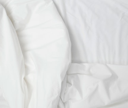 Close‑up of white, slightly wrinkled bed sheets
