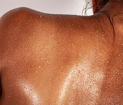 Close‑up of a sweaty back with visible moisture droplets symbolising heavy sweating