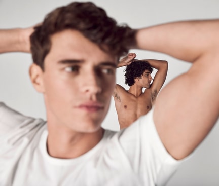 Two people with raised arms against a bright background; focus on the underarm area as a symbolic image for removing sweat stains