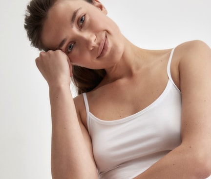 Person wearing a white CALIDA spaghetti strap top from the Natural Comfort collection against a light background.