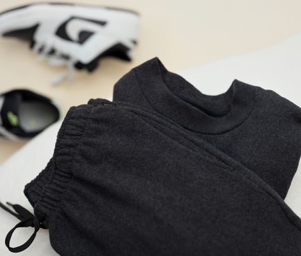 CALIDA RMX LOUNGE TIME OFF Sweatshirt liegt auf einer weissen Couch. Im Hintergrund sieht man weisse Sneaker.